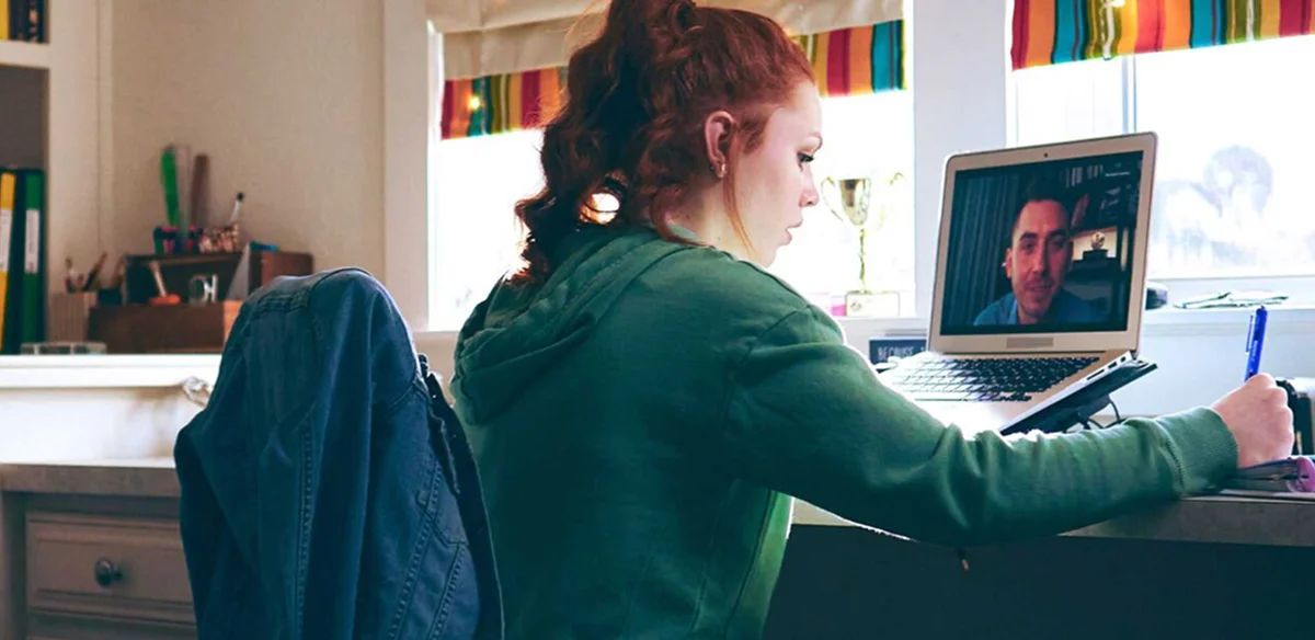 girl in virtual class writing in the notebook