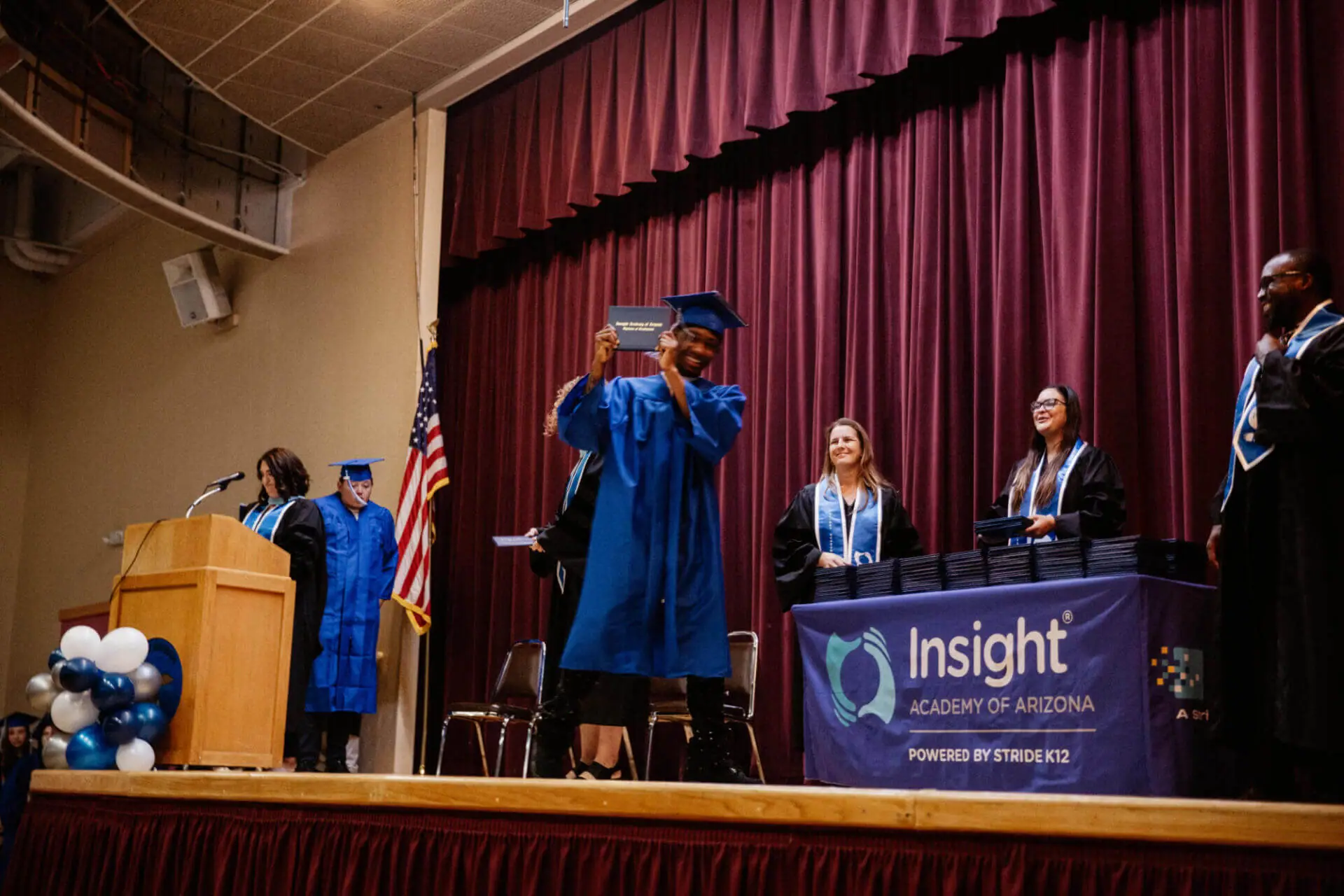 JaQuan celebrates on stage after receiving his high school diploma at the Insight Academy of Arizona graduation ceremony.