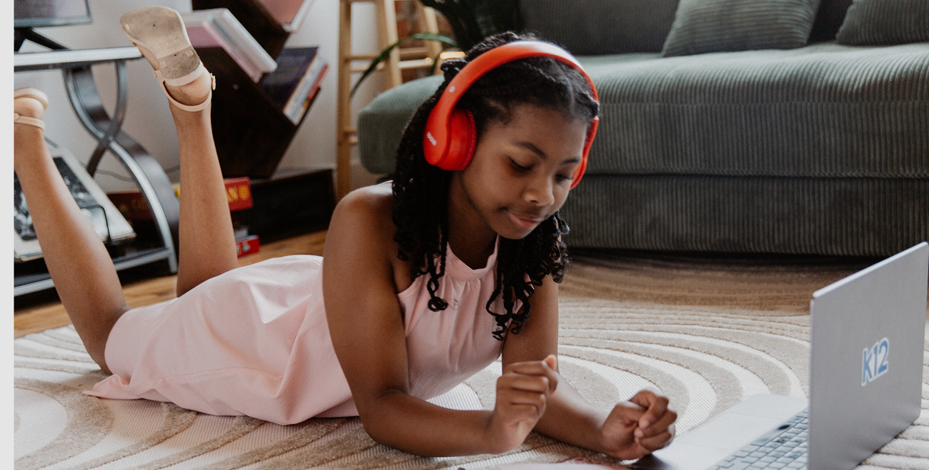 Student working with her laptop at home wearing a red pair of headphones