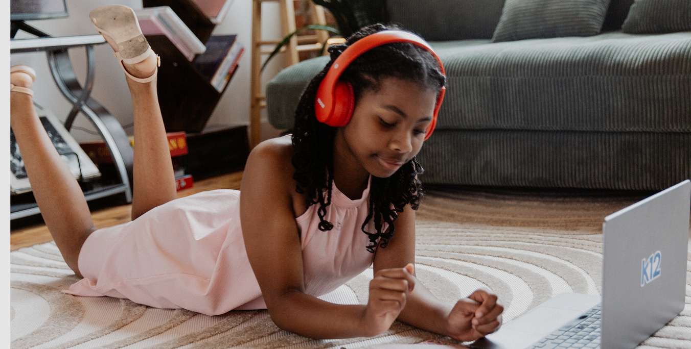 Girl studying with her laptop at home wearing a red pair of headphones