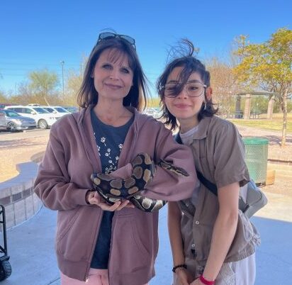 Veterinary Science teacher Jessica Berger and ISAZ student Linda Hernandez check out a slithery special guest at Family Fun Day.